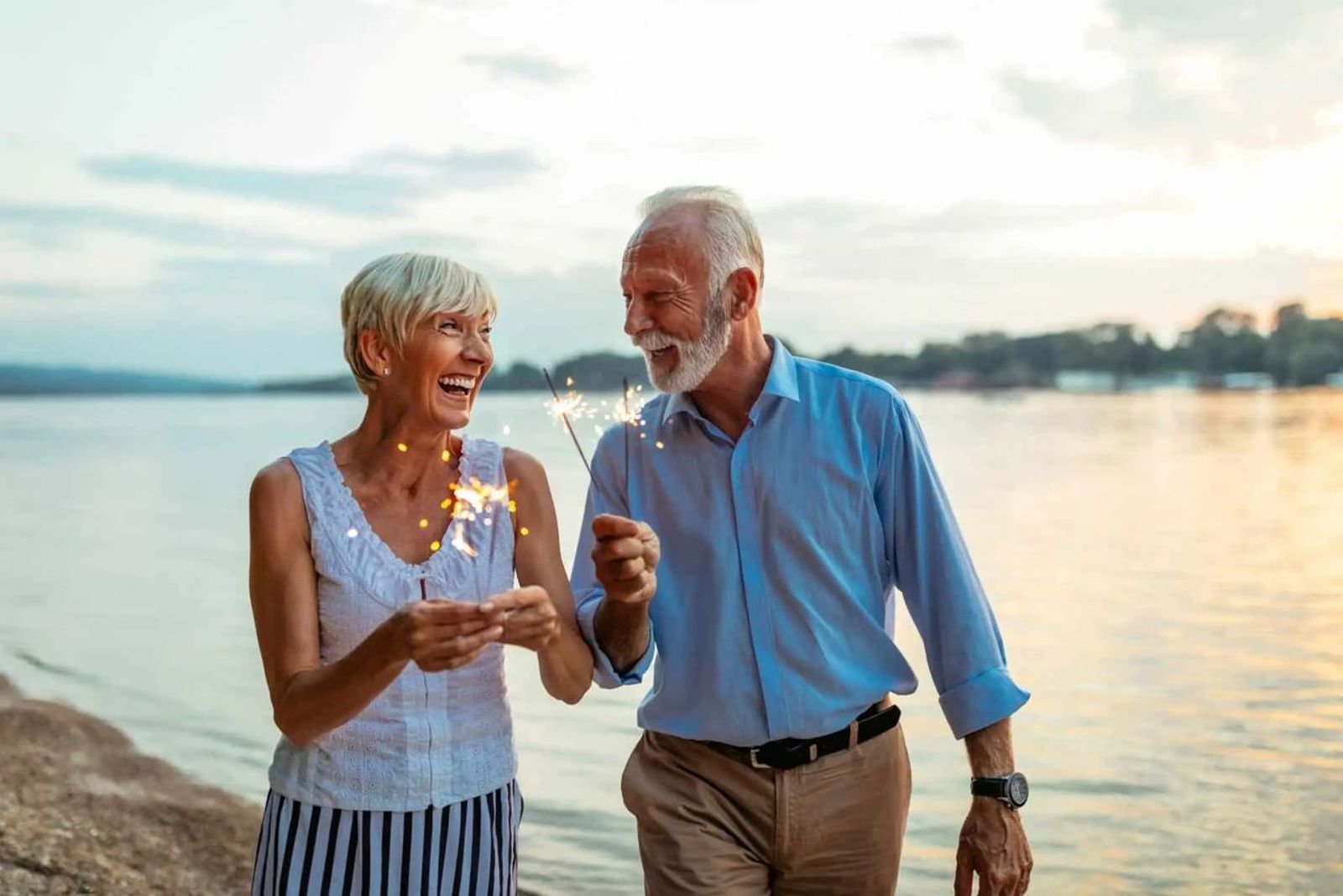 Retired couple by lake holding sparklers