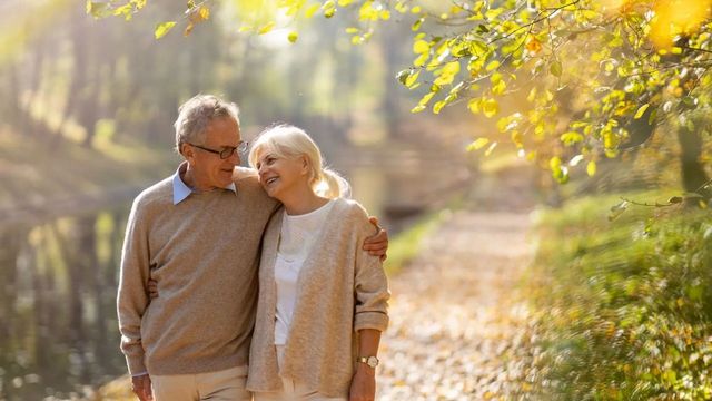 Retired couple walking by the river smiling