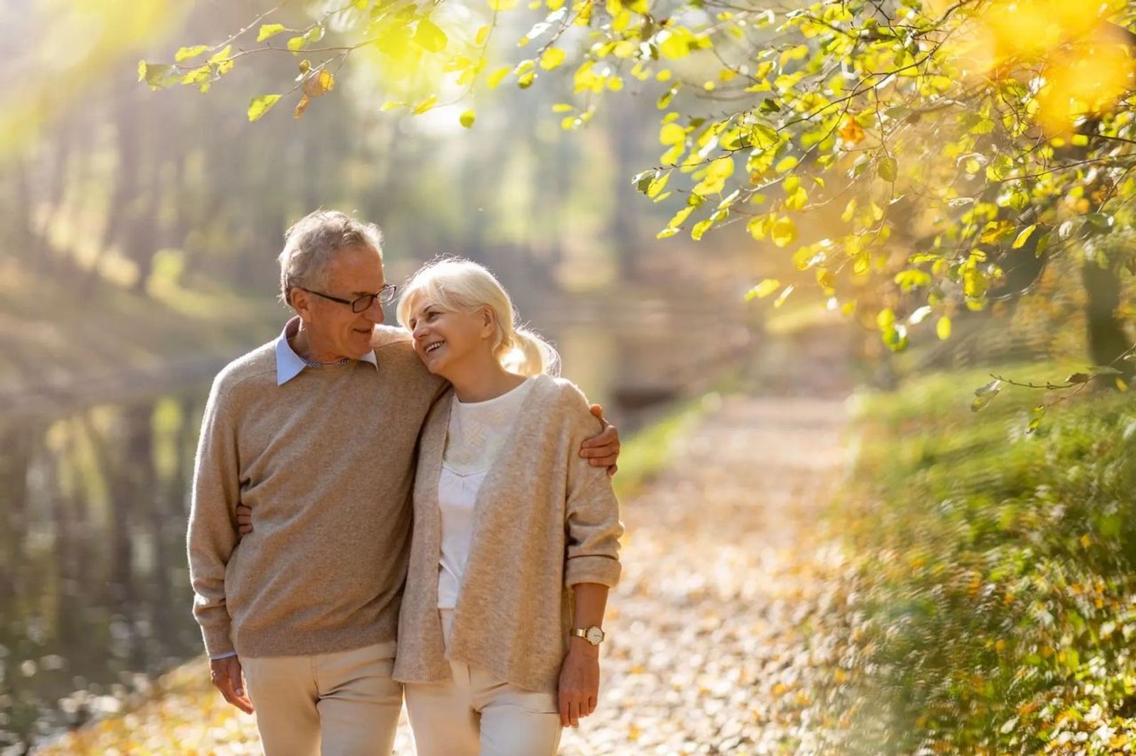 Retired couple walking by the river smiling