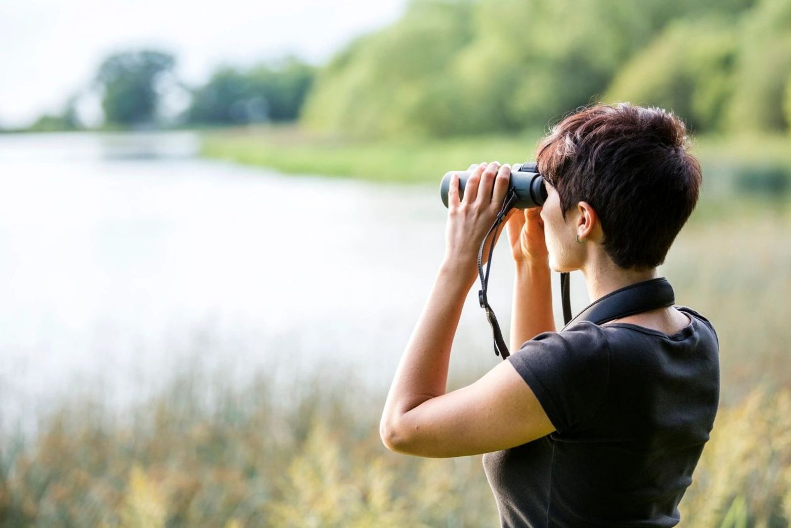 Woman looking through binoculars at a lake