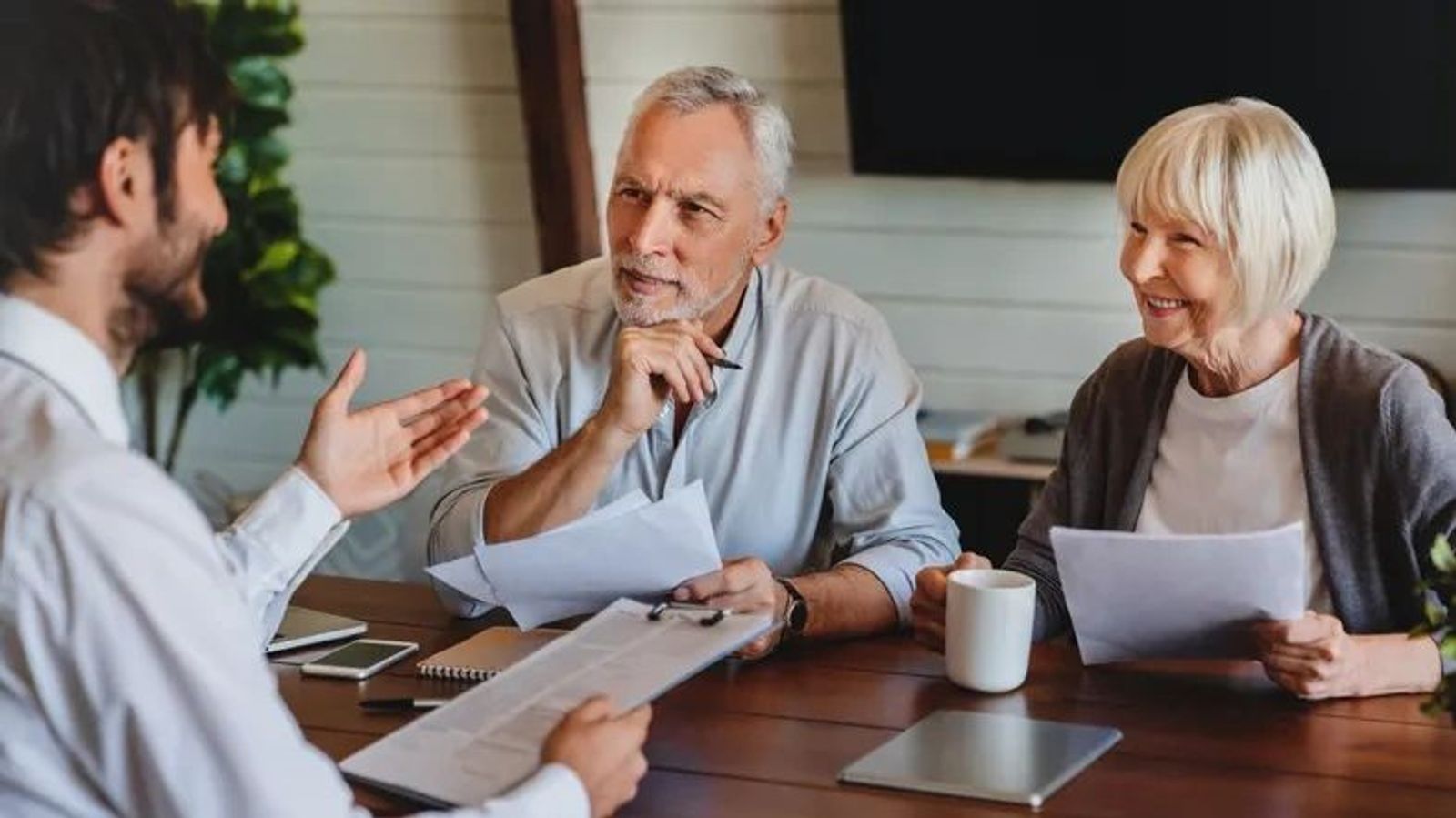 A warm, professional meeting with a financial advisor sitting across from a retired couple, reviewing retirement plans or financial documents.