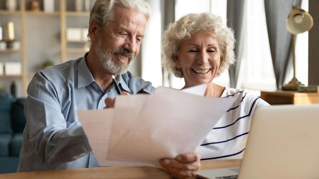 retired couple smiling working on paperwork