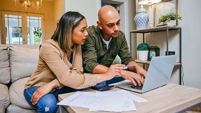 Couple is sitting down on couch working on their financial investments and budget