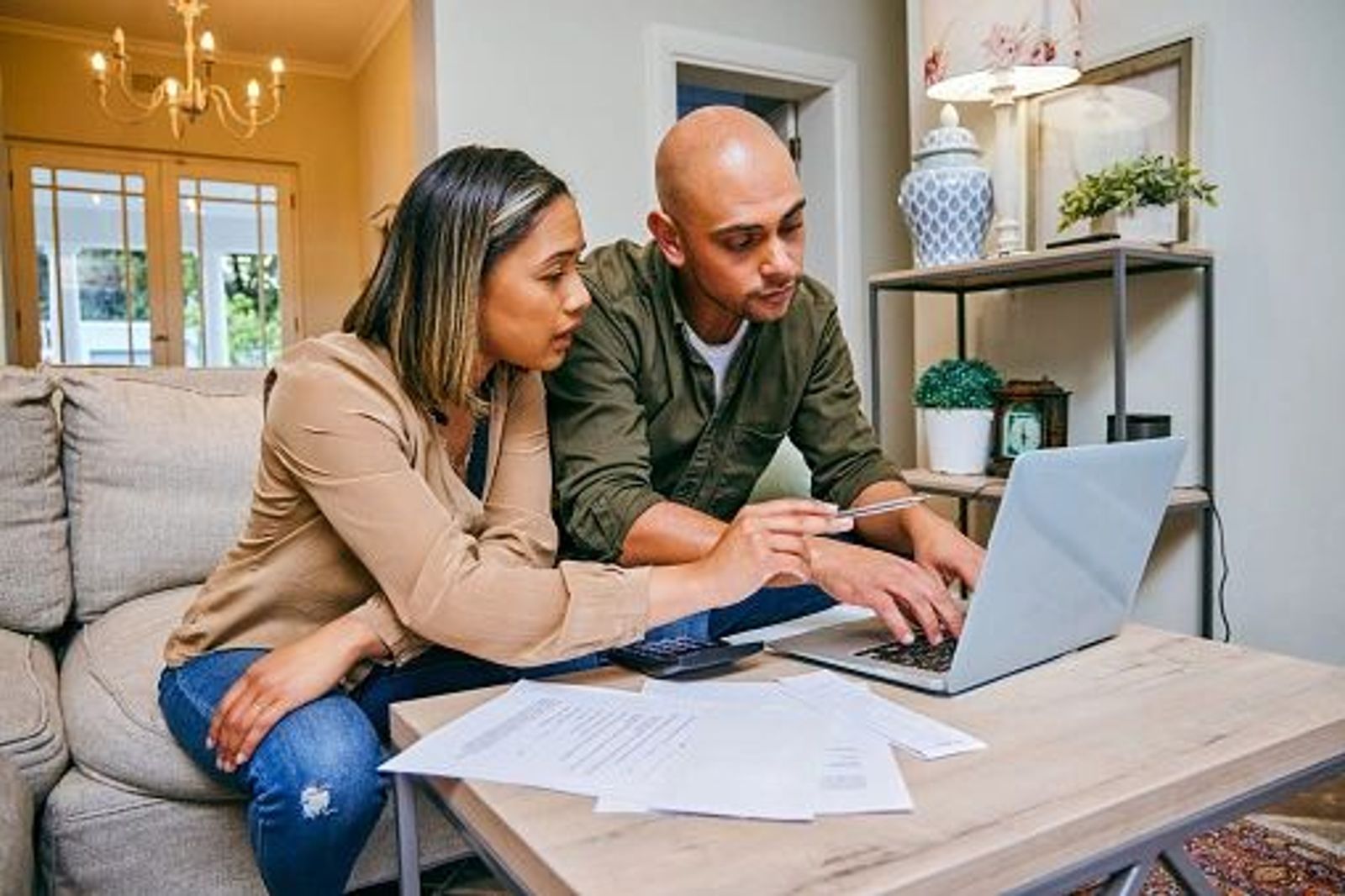 Couple is sitting down on couch working on their financial investments and budget