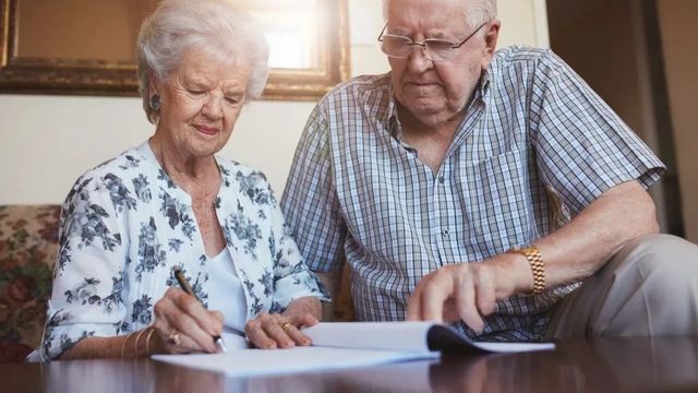 Retired couple signing will in living room