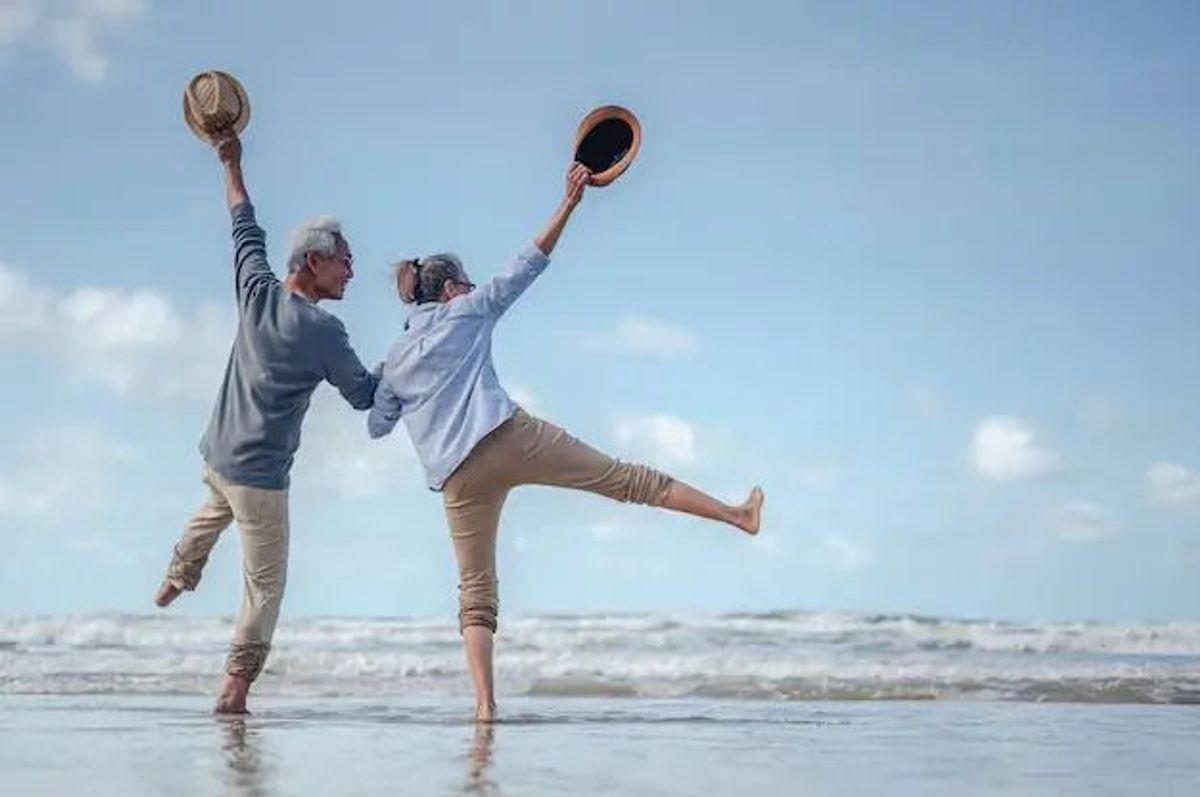 Happy retired couple celebrating at the beach