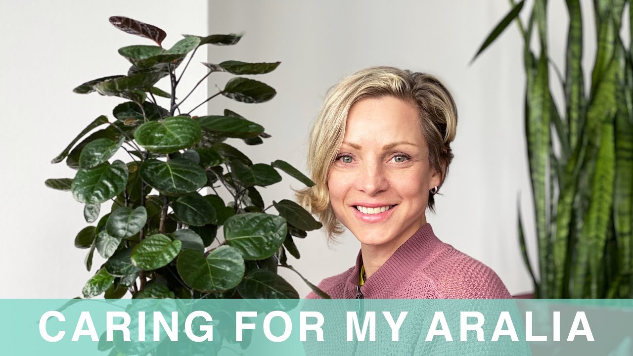 Juliette smiling next to a large aralia plant