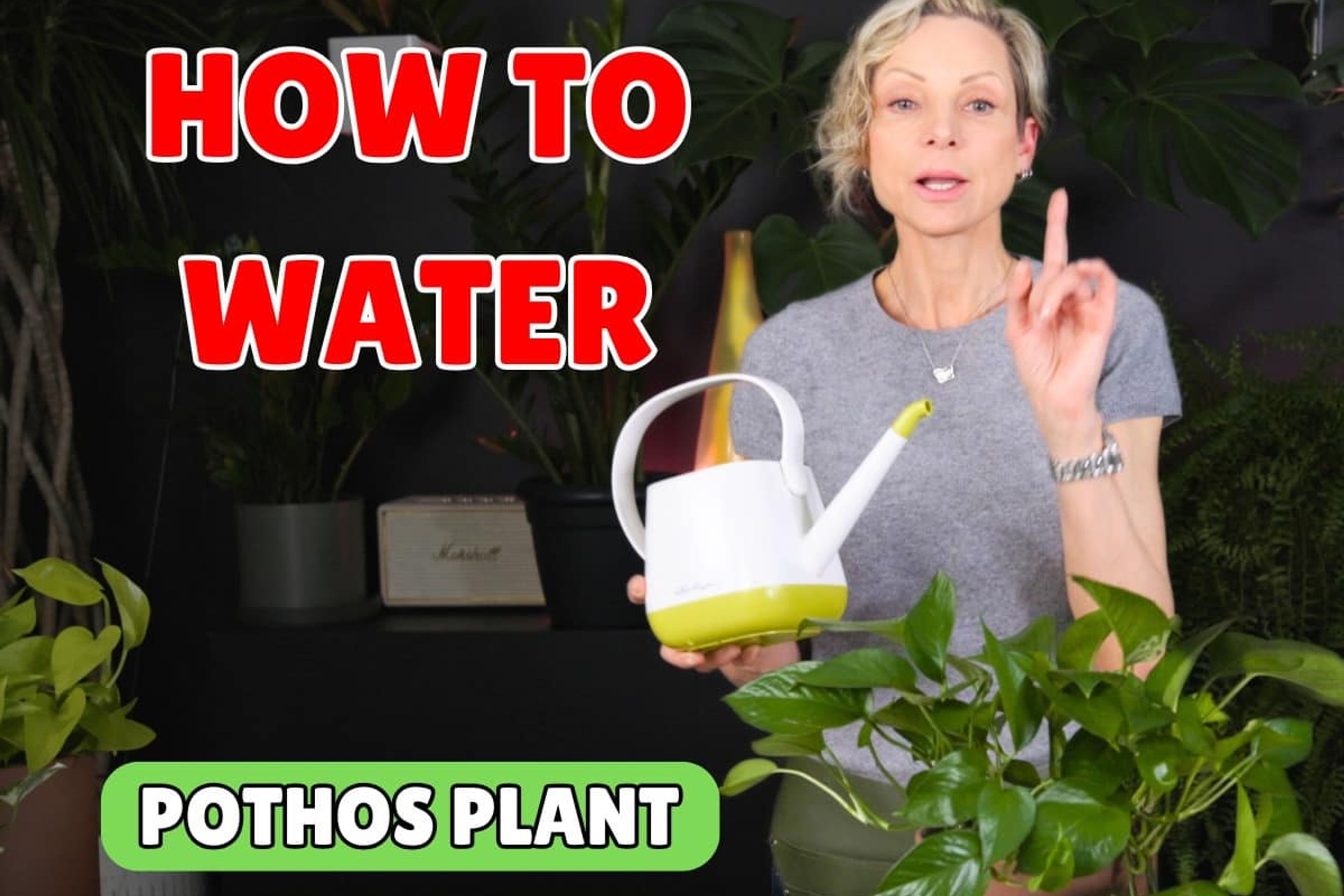 Woman demonstrating how to water a pothos plant indoors.