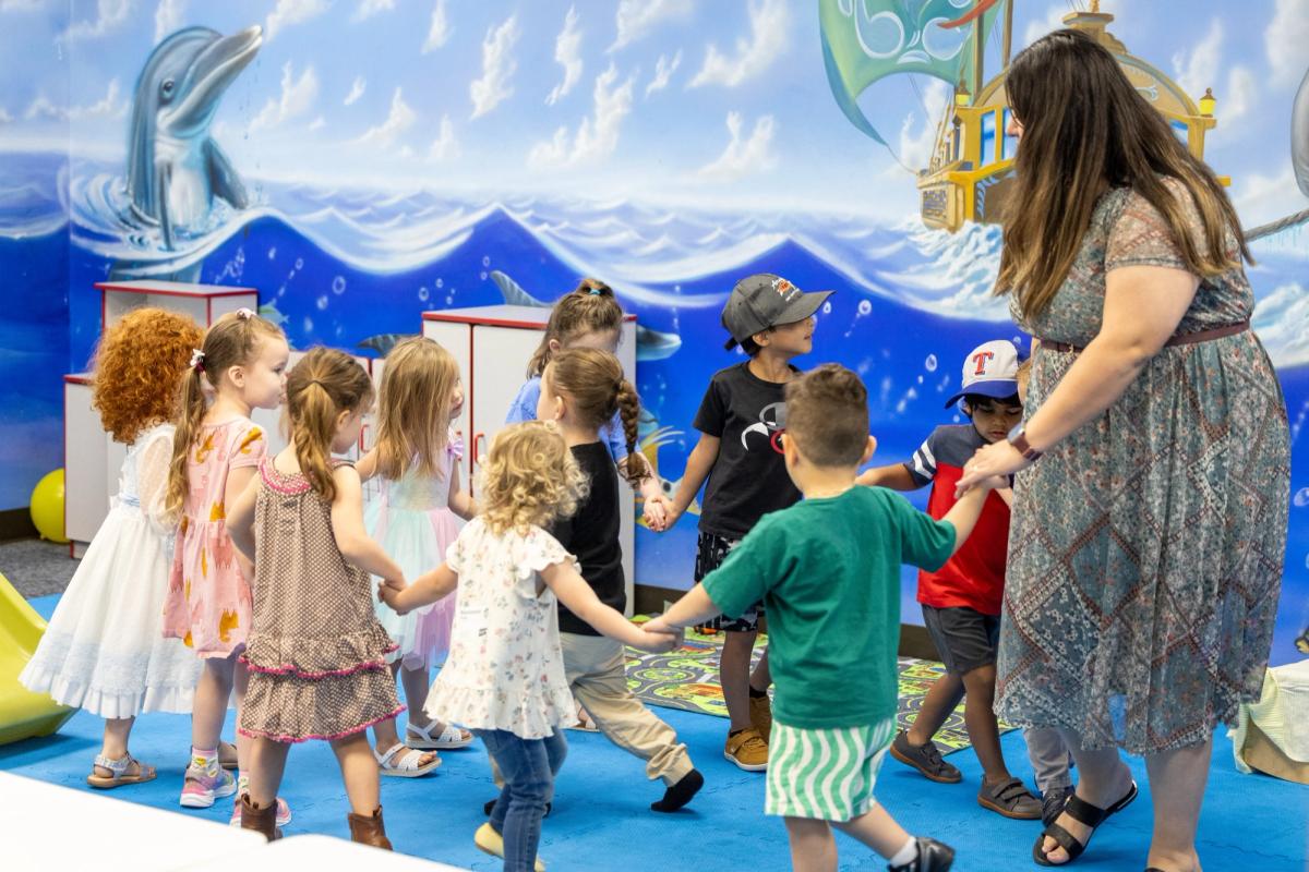 Kids and a leader dancing in a circle in the classroom