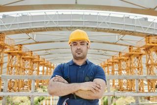 Worker with harness implementing fall protection protocol on a construction site.