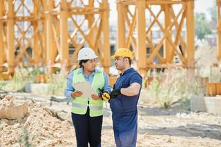 Construction site supervisor conducting a safety toolbox talk with workers in PPE.