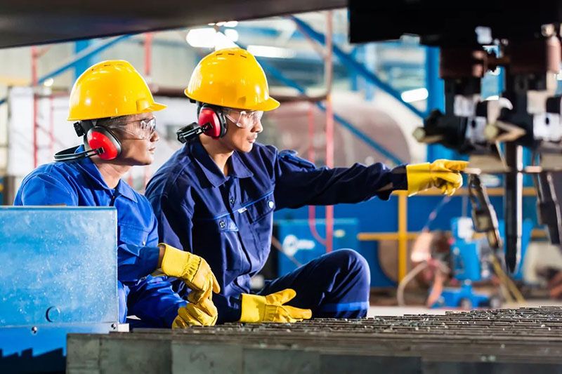 Worker in PPE operating machinery in a high-risk manufacturing environment.”