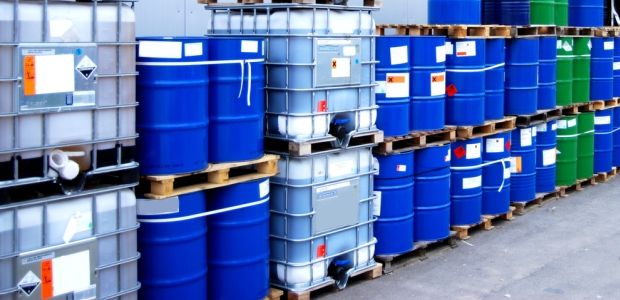 EHS professional inspecting labeled chemical storage containers.
