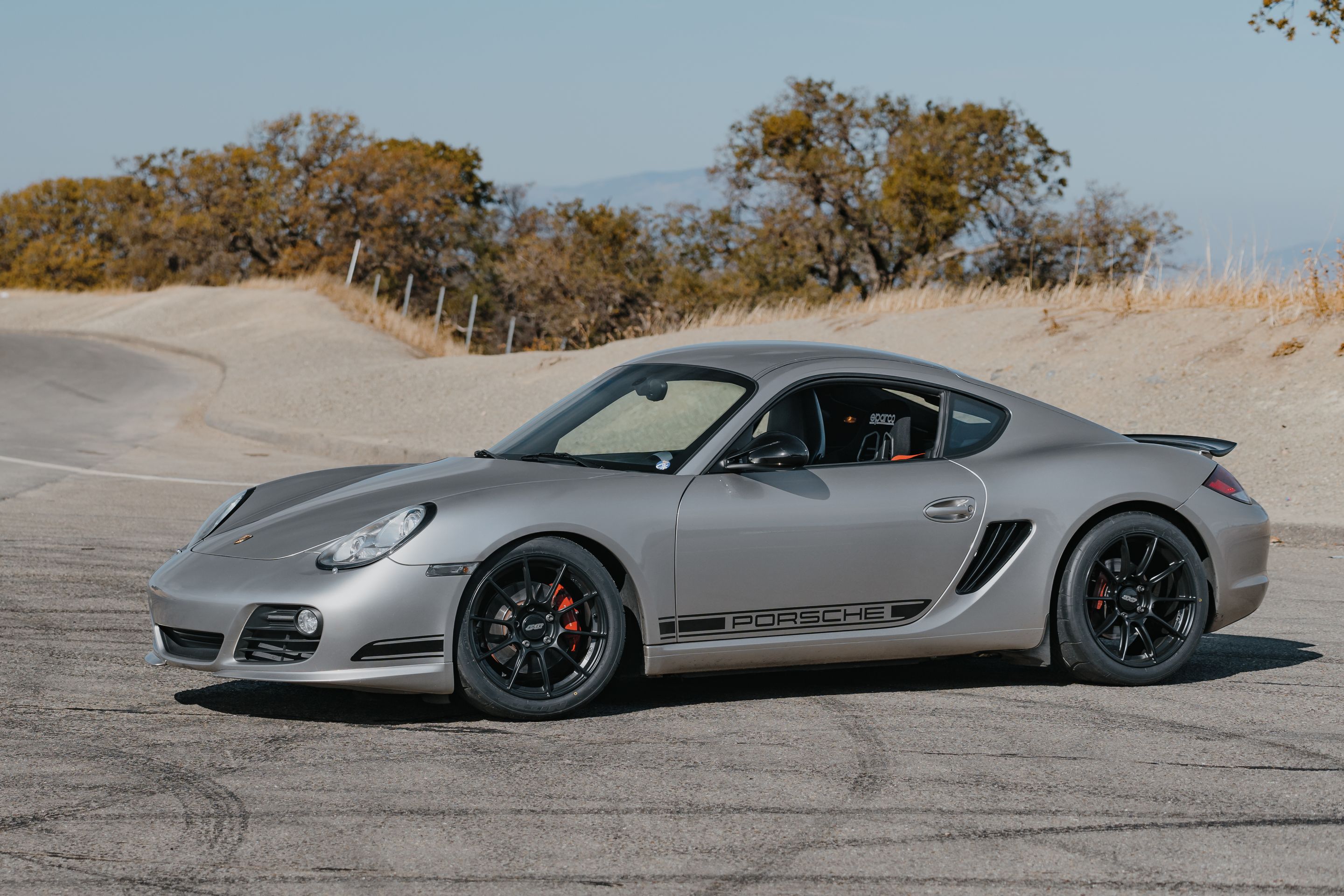 Silver Porsche 987 Cayman R with 18" SM-10RS Apex wheels in Satin Black