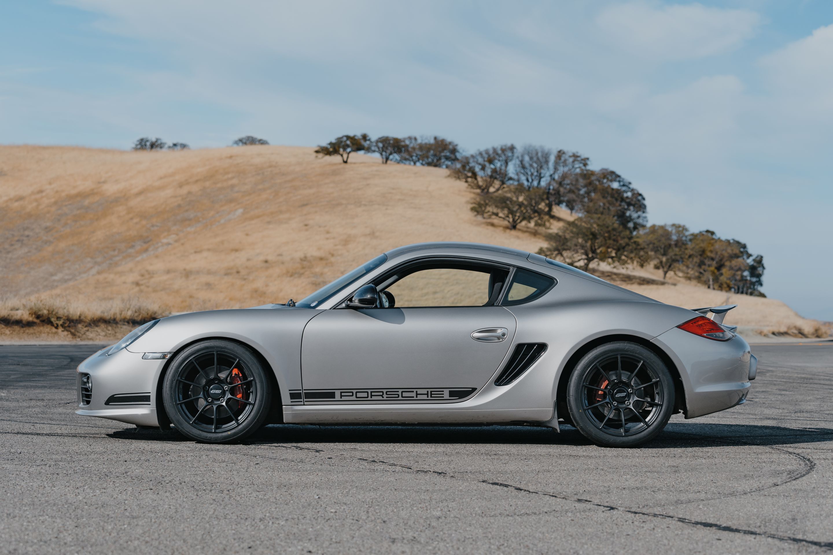Silver Porsche 987 Cayman R with 18" SM-10RS Apex wheels in Satin Black