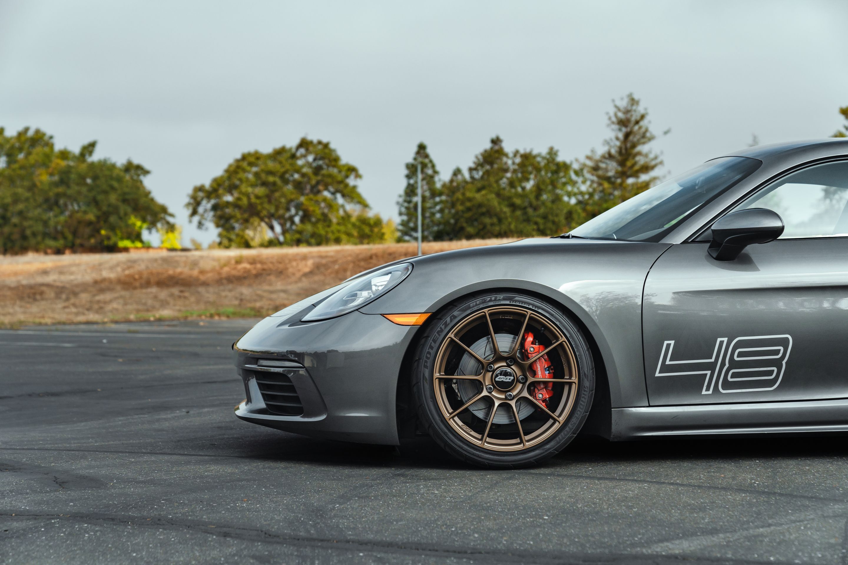 Grey Porsche 718 Cayman S with 19" SM-10RS Apex wheels in Satin Bronze