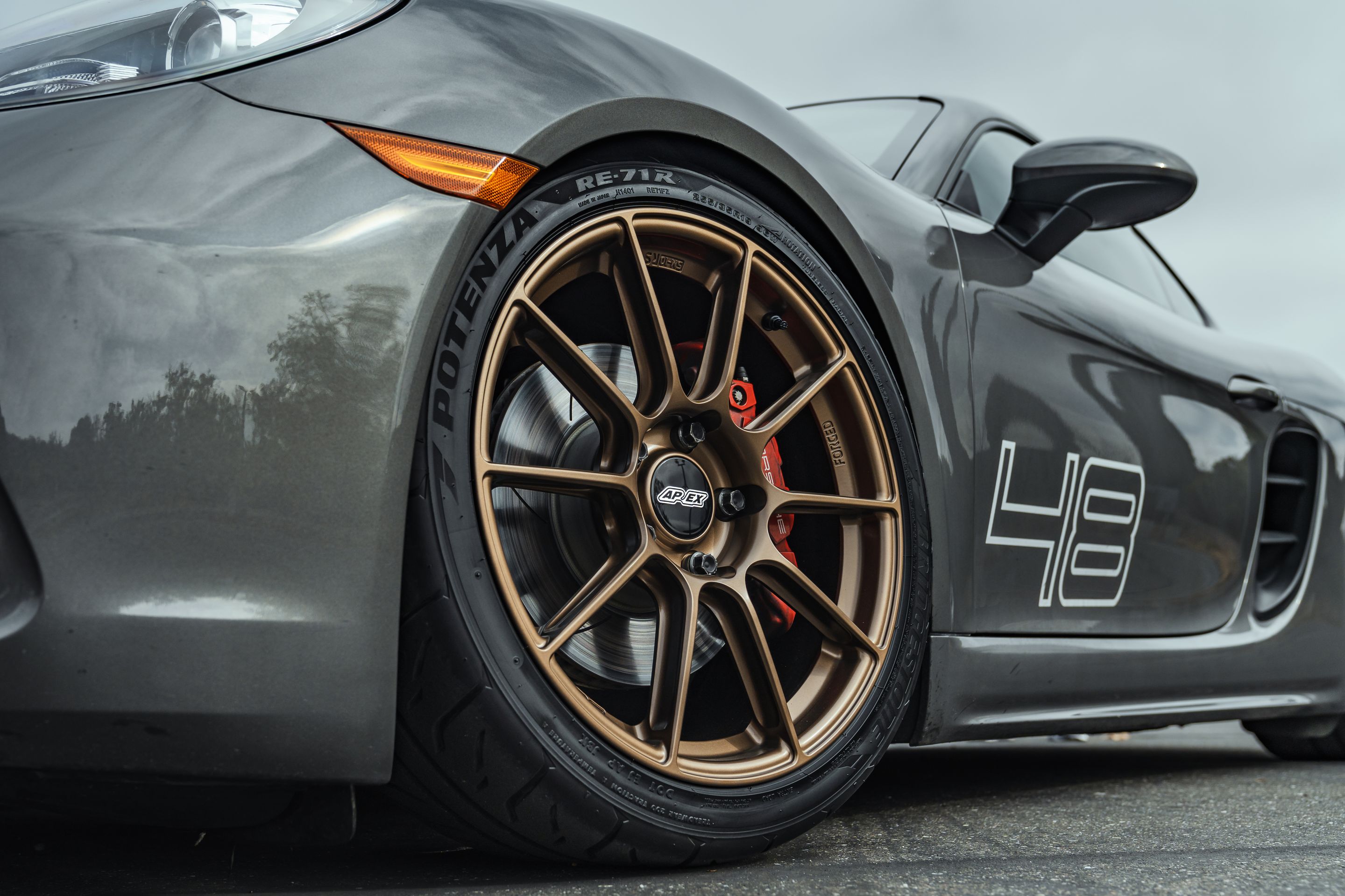 Grey Porsche 718 Cayman S with 19" SM-10RS Apex wheels in Satin Bronze