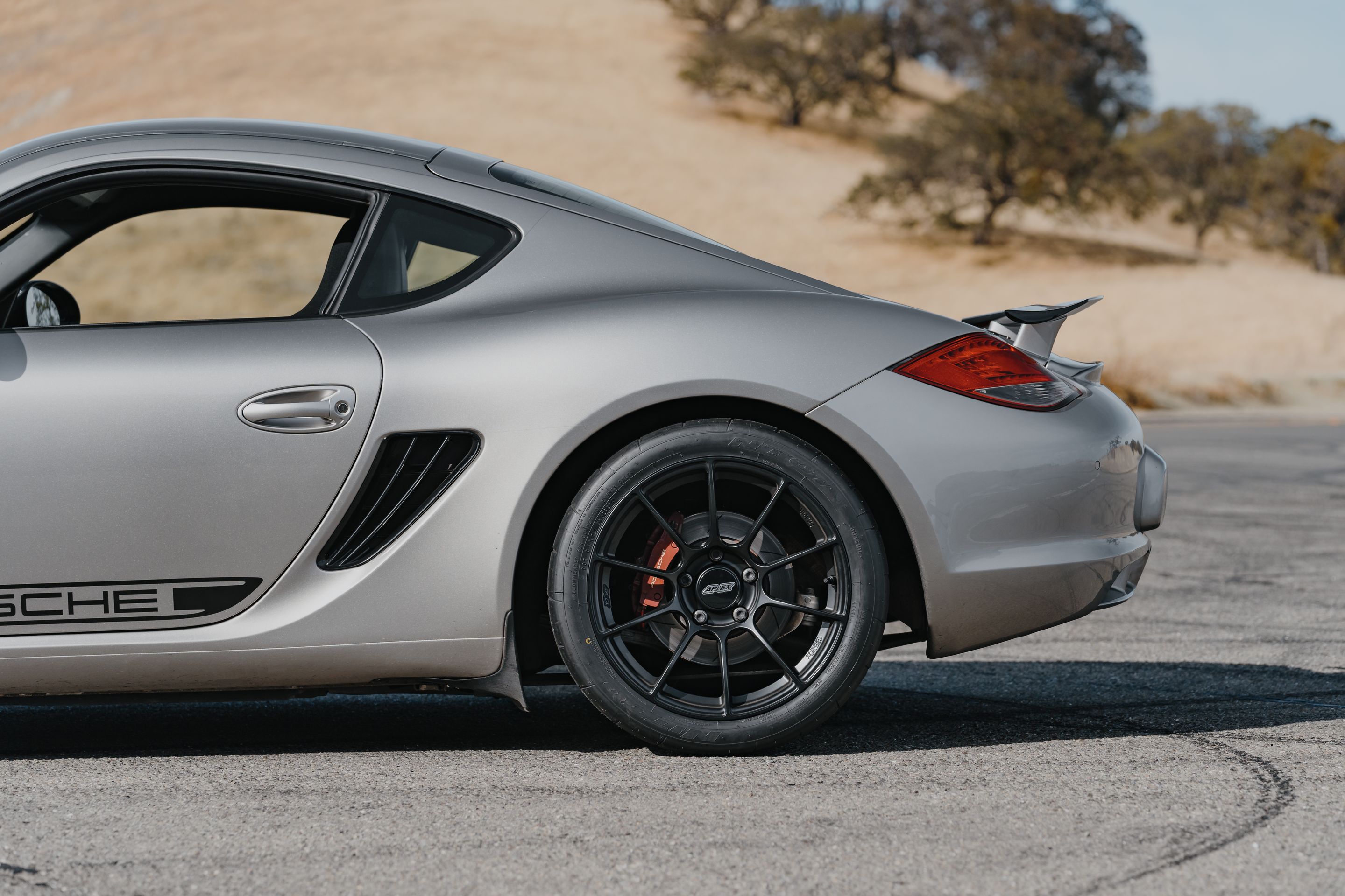 Silver Porsche 987 Cayman R with 18" SM-10RS Apex wheels in Satin Black