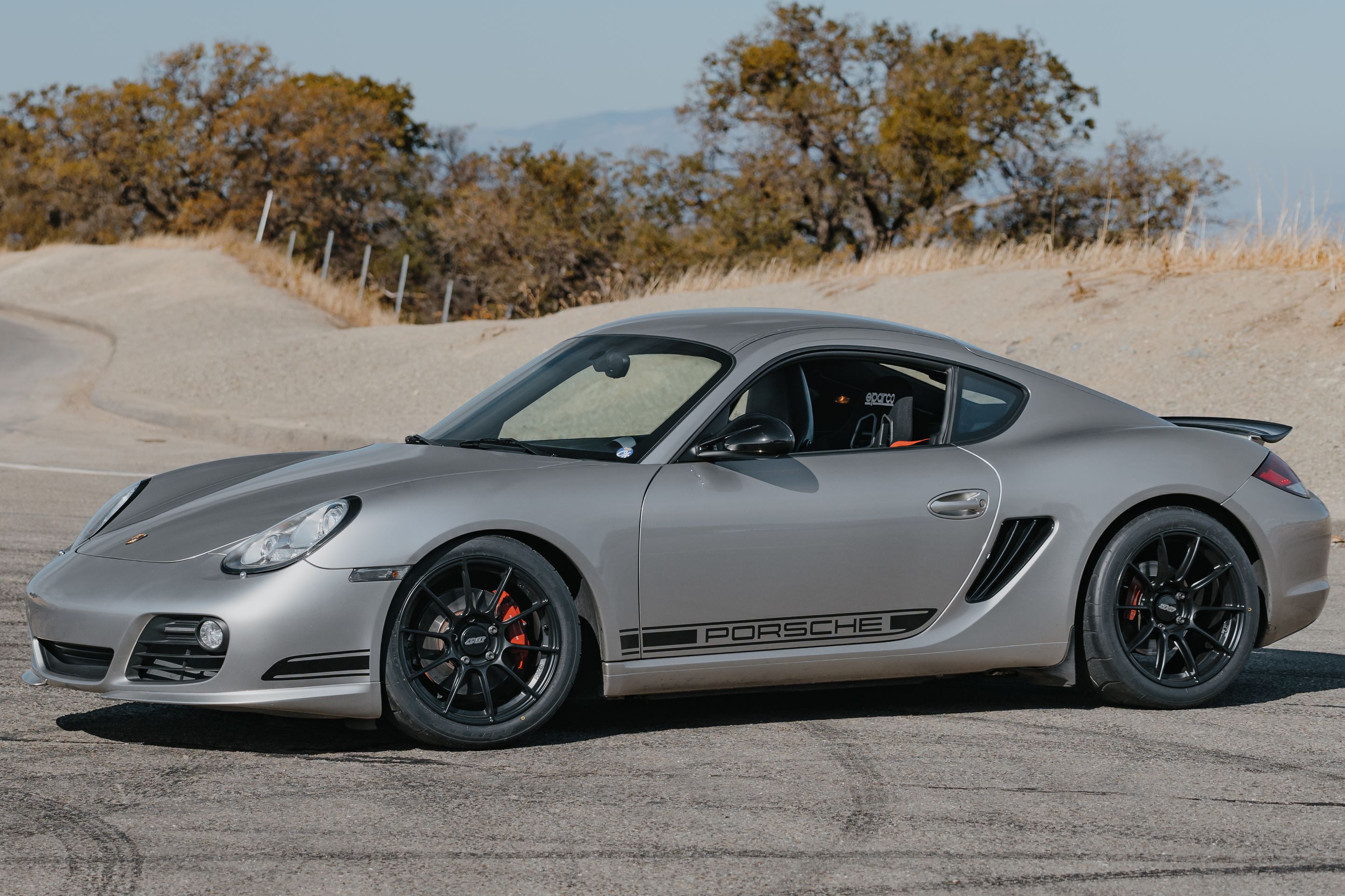 Silver Porsche 987 Cayman R with 18" SM-10RS Apex wheels in Satin Black