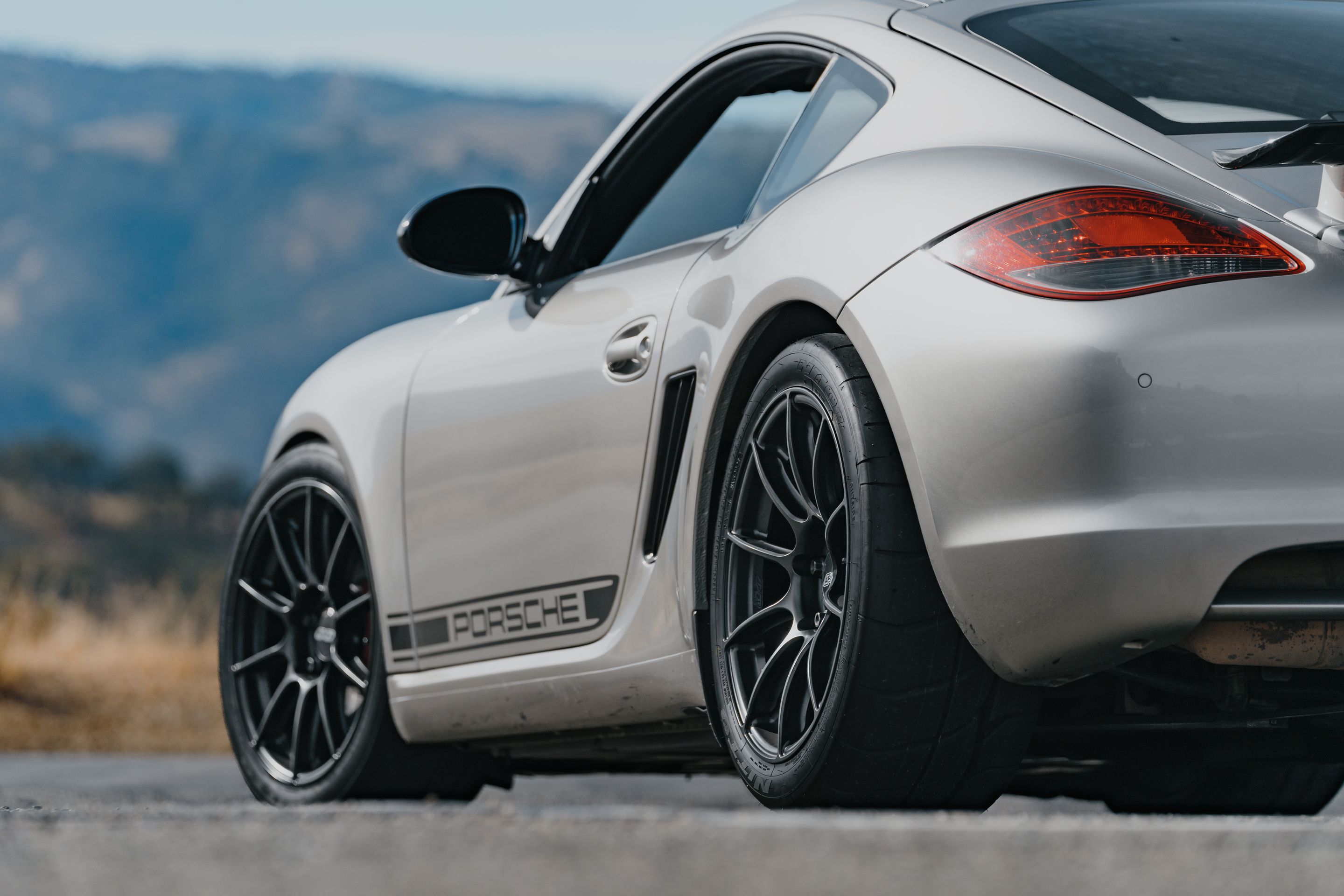 Silver Porsche 987 Cayman R with 18" SM-10RS Apex wheels in Satin Black