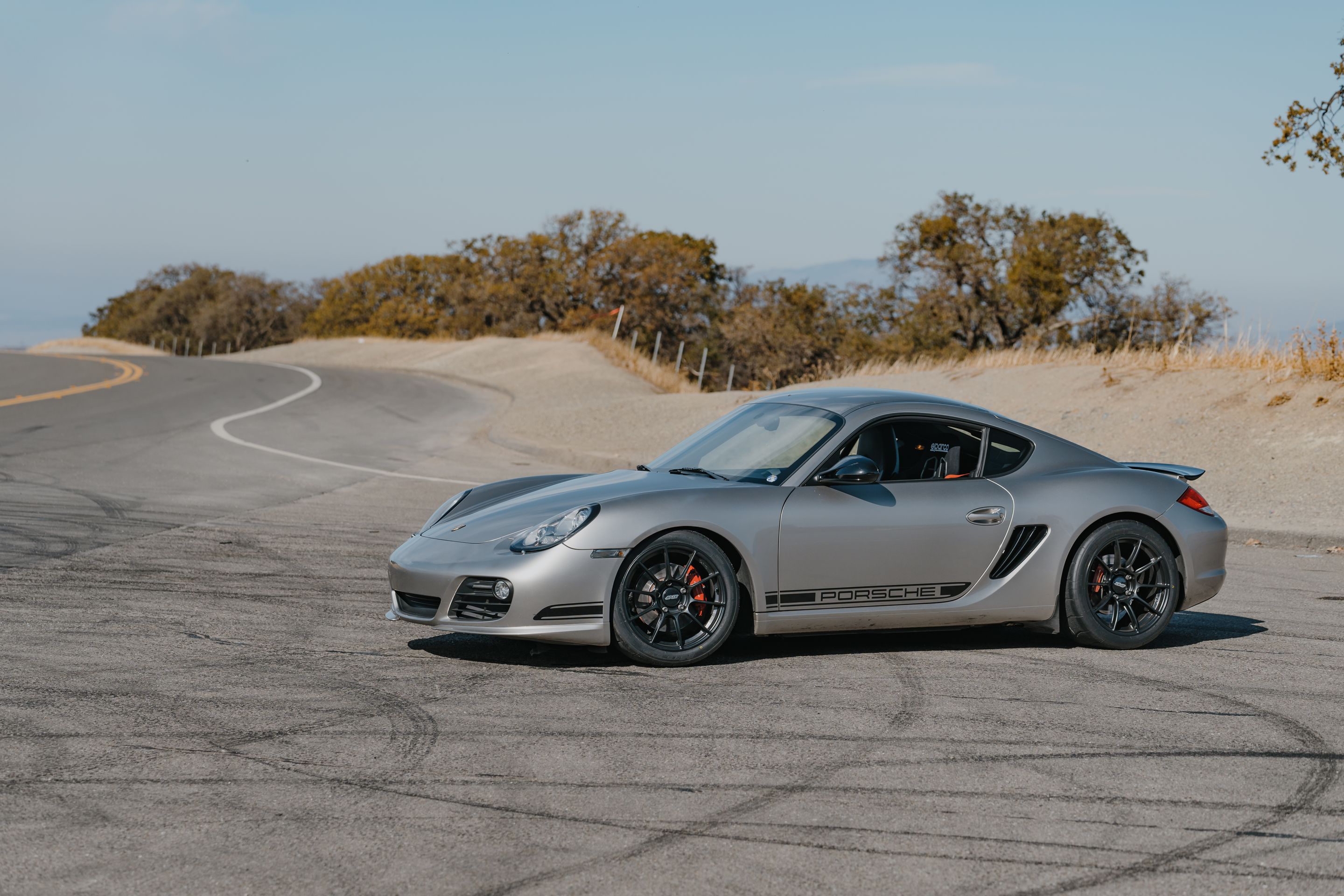 Silver Porsche 987 Cayman R with 18" SM-10RS Apex wheels in Satin Black