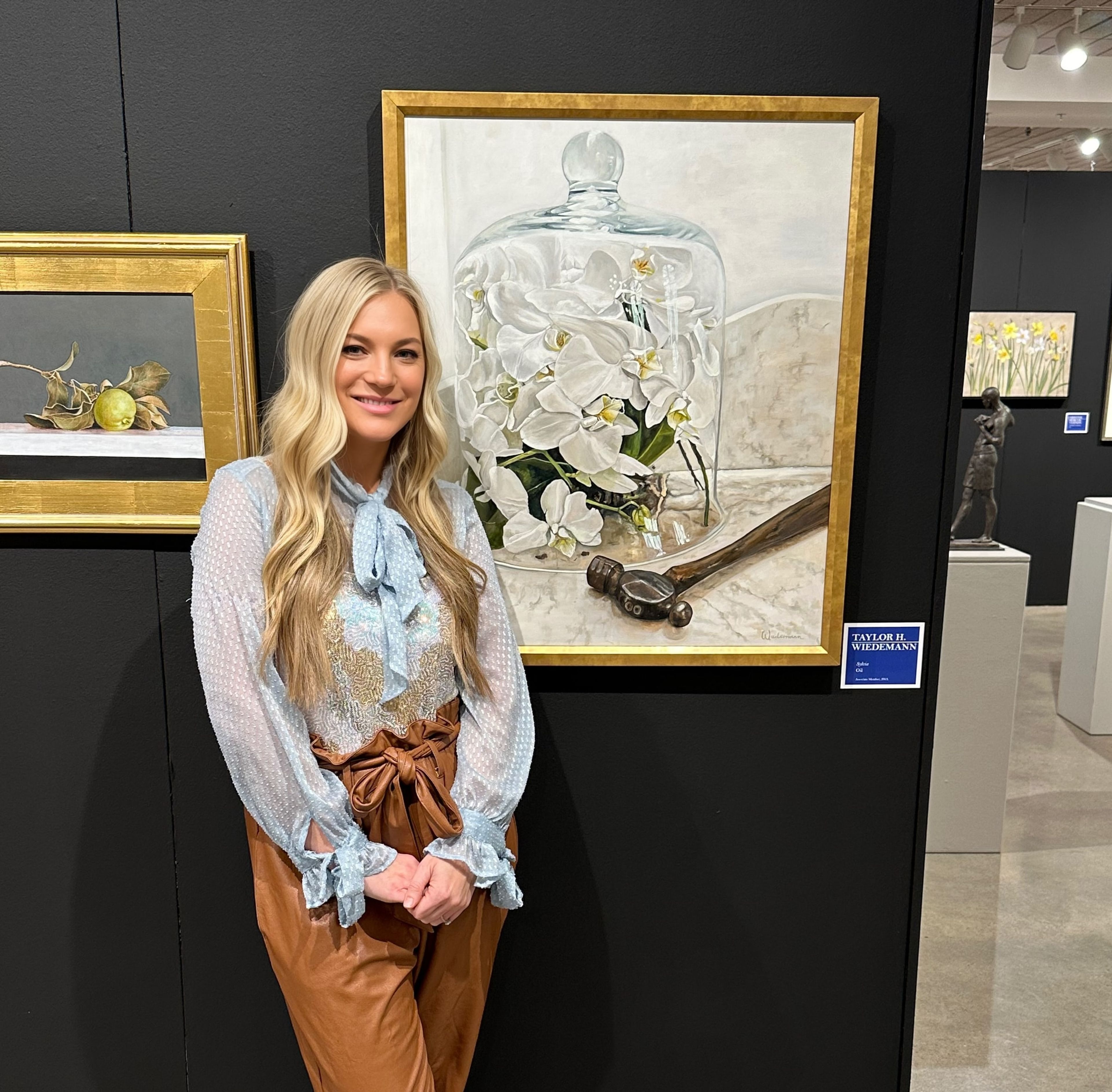 Taylor Wiedemann beside one of her paintings