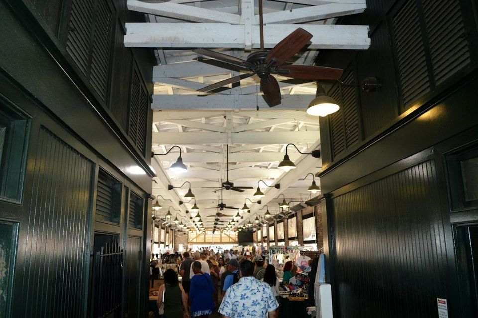 A crowd of people walking through a covered market with dark wooden walls