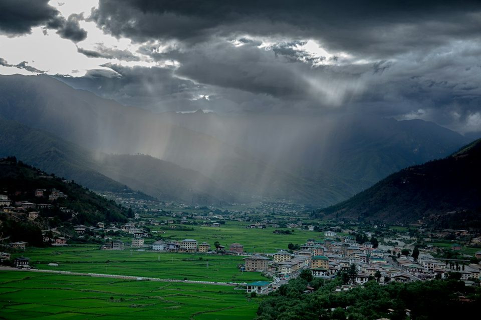 Sunlight streams through stormy clouds over a valley town