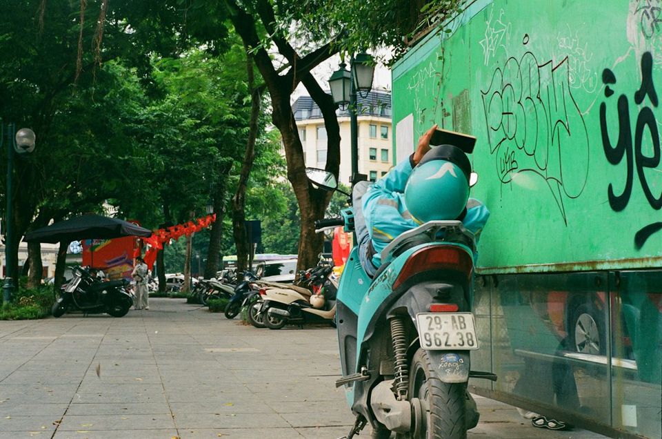 Man in blue jacket resting on a scooter outdoors