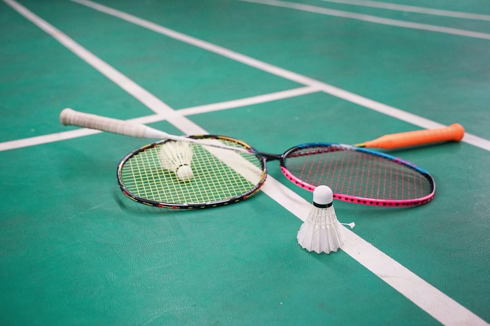 Two badminton rackets and shuttlecocks on a green court