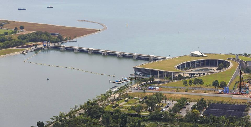 Aerial view of the Marina Barrage dam and its green-roofed visitor centre separating Marina Reservoir from the sea in Singapore.
