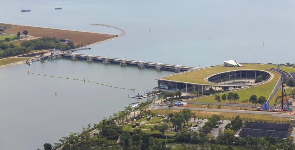 Aerial view of the Marina Barrage dam and its green-roofed visitor centre separating Marina Reservoir from the sea in Singapore.
