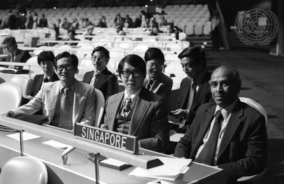 A young Tommy Koh seated at a UN delegation desk in the 1970s, alongside a fellow Singaporean diplomat.