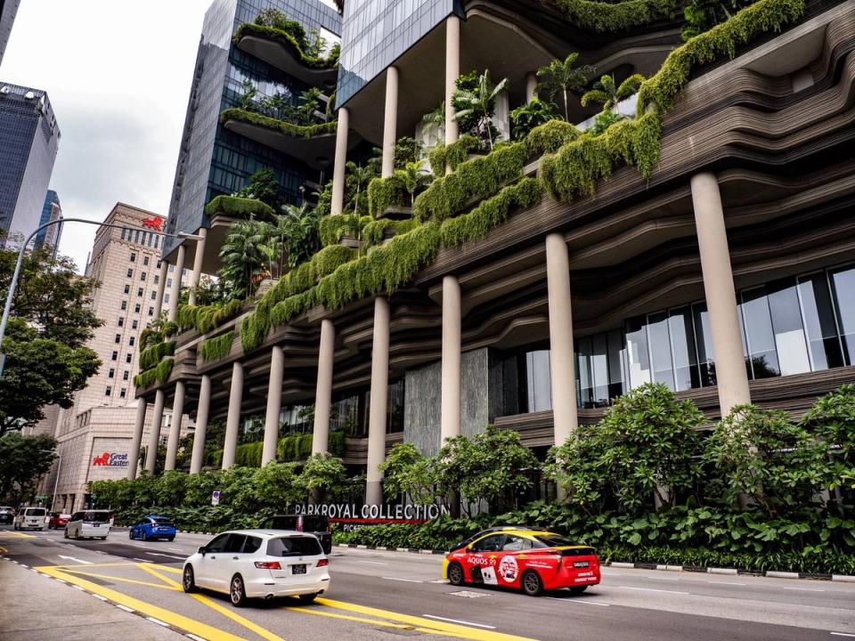 The Parkroyal Collection Pickering hotel in Singapore, its terraced facade covered in hanging plants and sky gardens above a street with passing cars.