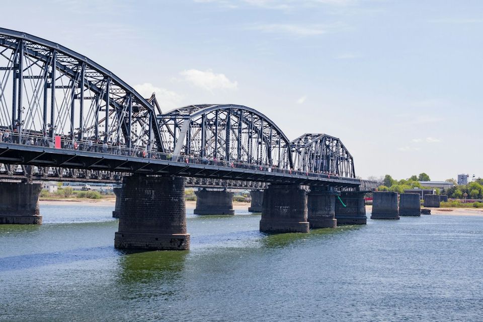 A steel bridge spans over a blue body of water