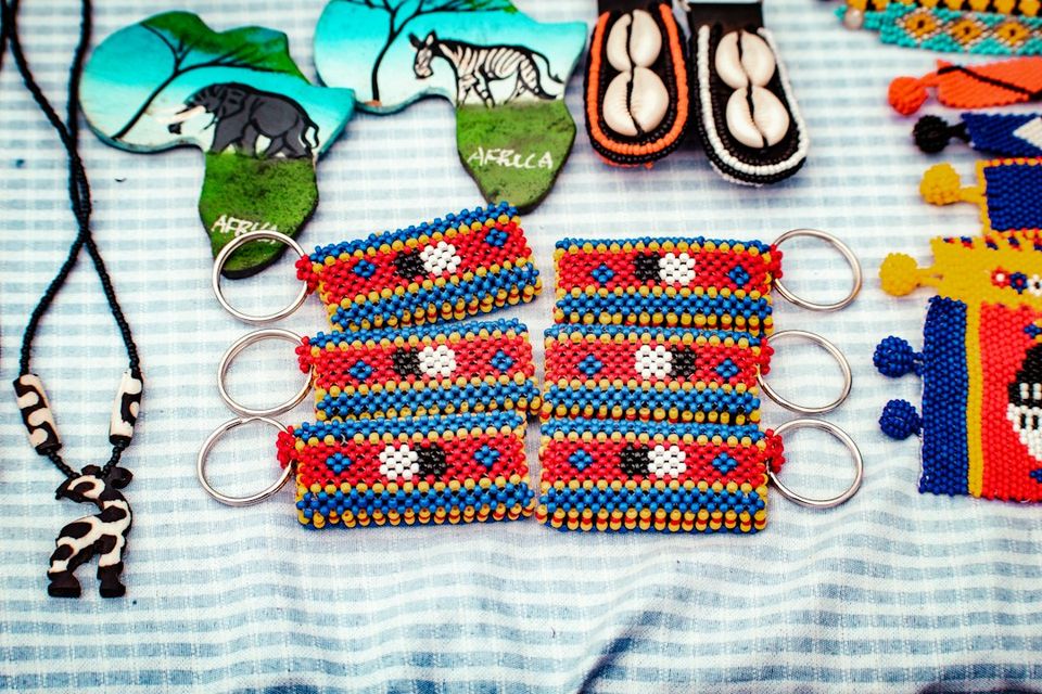 Beaded keychains with red, blue, and yellow patterns arranged on a blue and white striped cloth