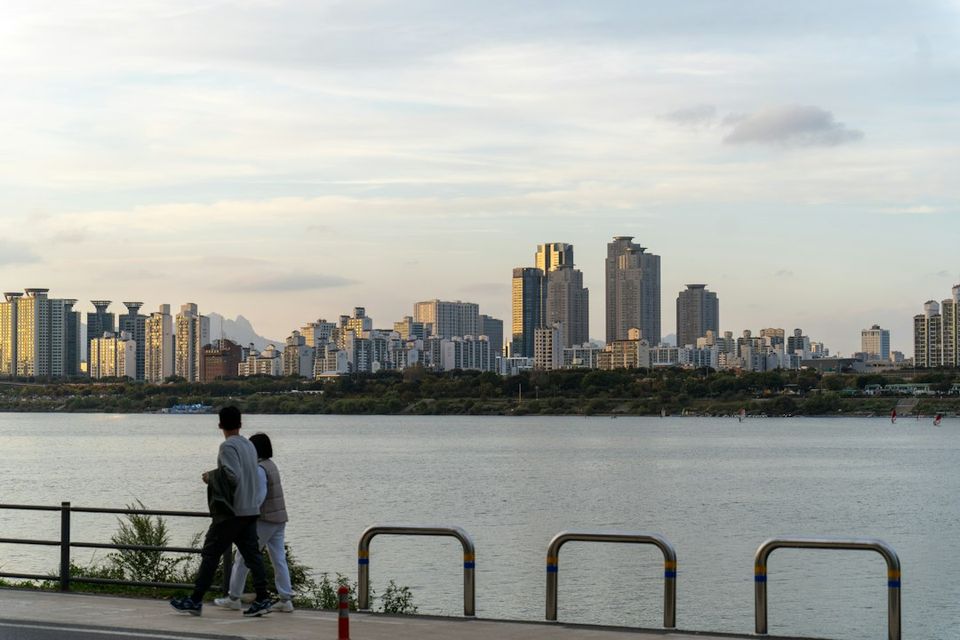 a man and a woman are walking by the water