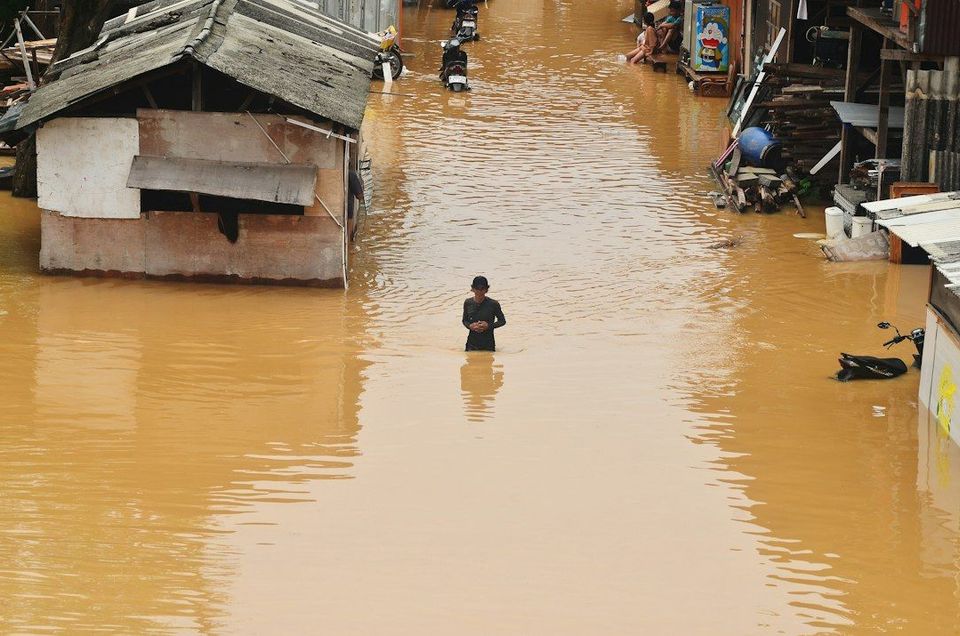 Flooding engulfs homes and a person stands in the water