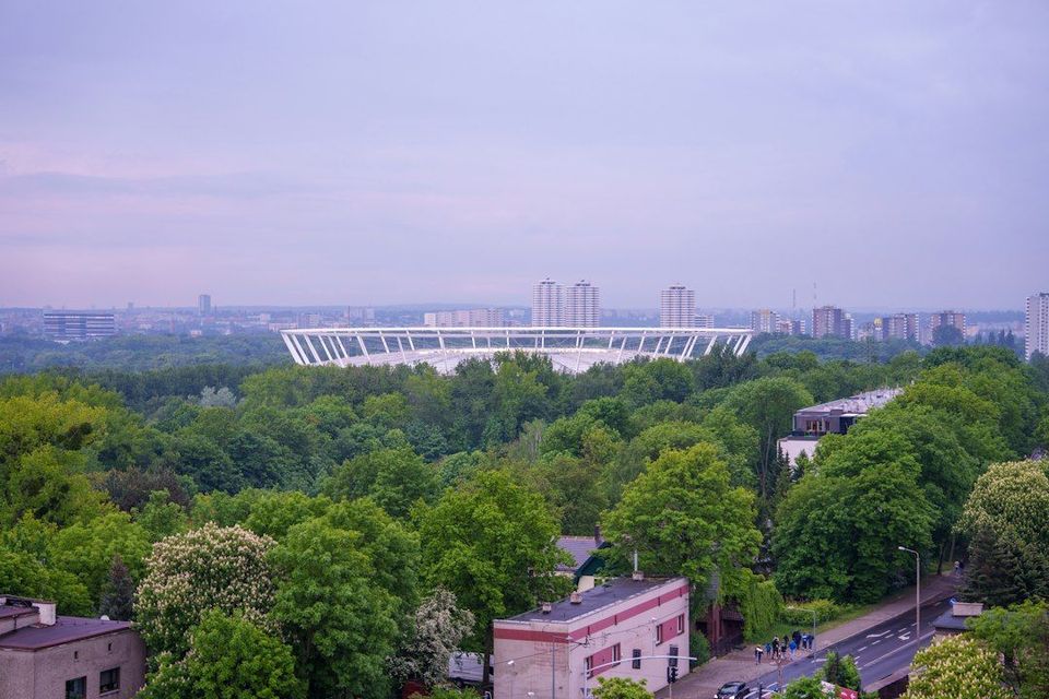 Modern stadium surrounded by lush green trees and buildings