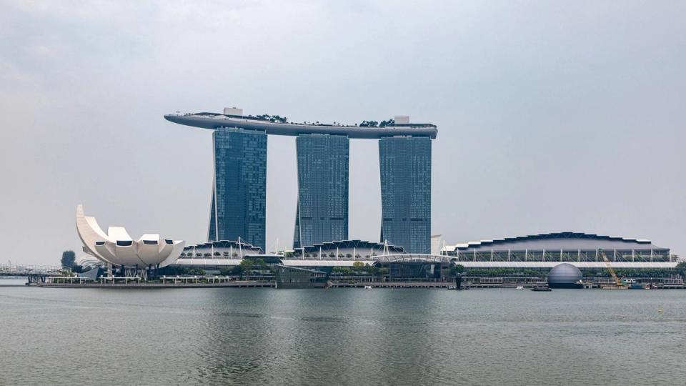 Marina Bay Sands hotel towers, the ArtScience Museum and the low waterfront complex housing the shops and expo centre, seen across Marina Bay by day.