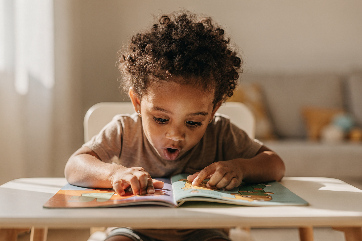Editorial photo of a toddler boy leaning over a lift-the-flap book with both hands lifting flaps simultaneously, used in an article about interactive toddler books