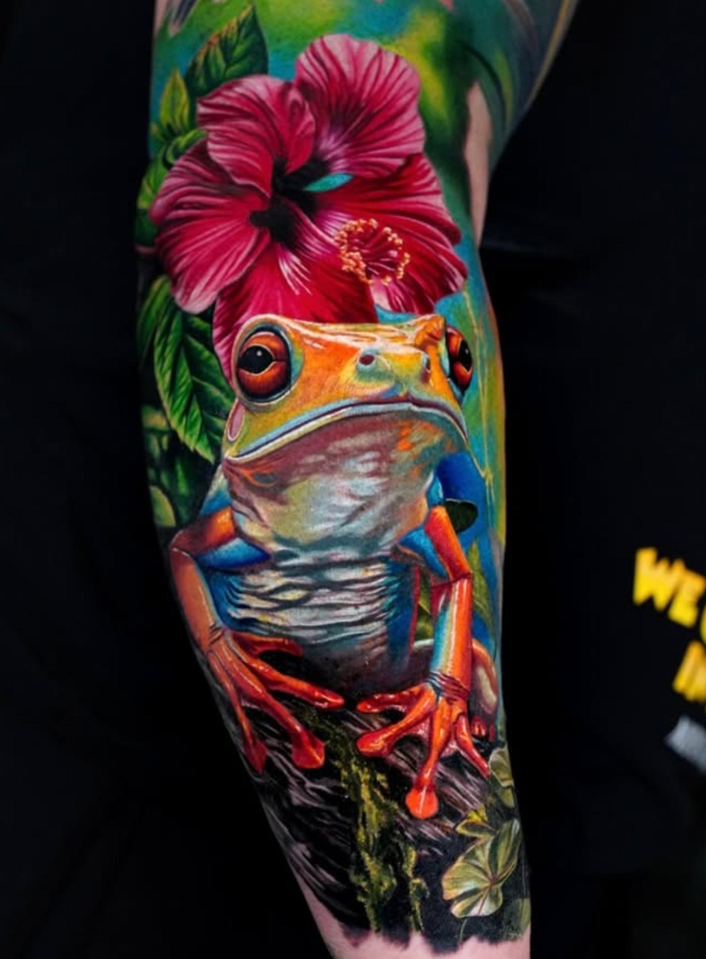 Colorful realistic tree frog tattoo on forearm with flower background