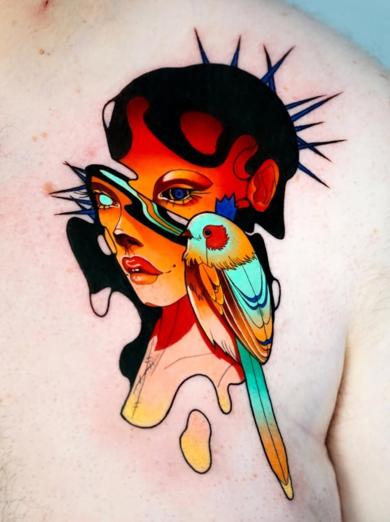 Colorful abstract New School tattoo on chest with face and bird.