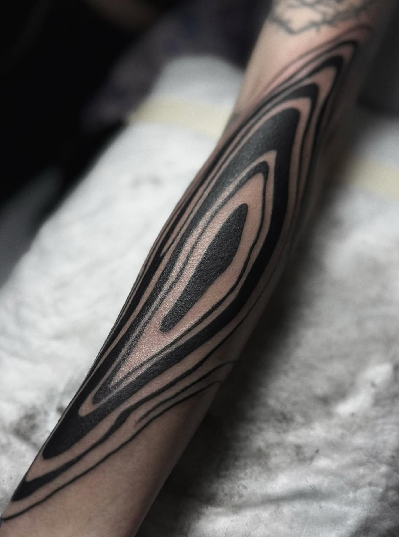 Abstract black and grey pattern tattoo on forearm.