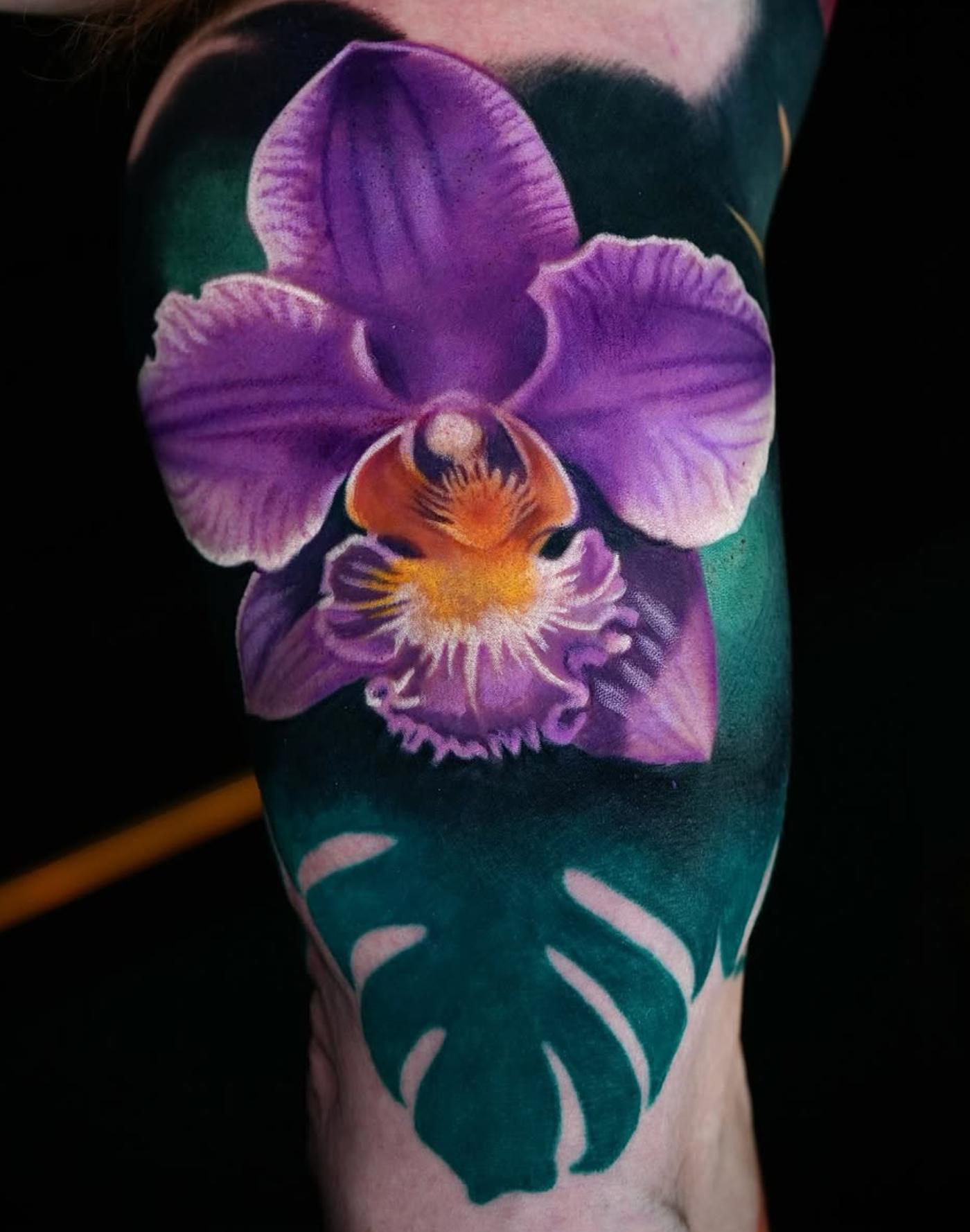 Colorful orchid tattoo on upper arm with realistic shading