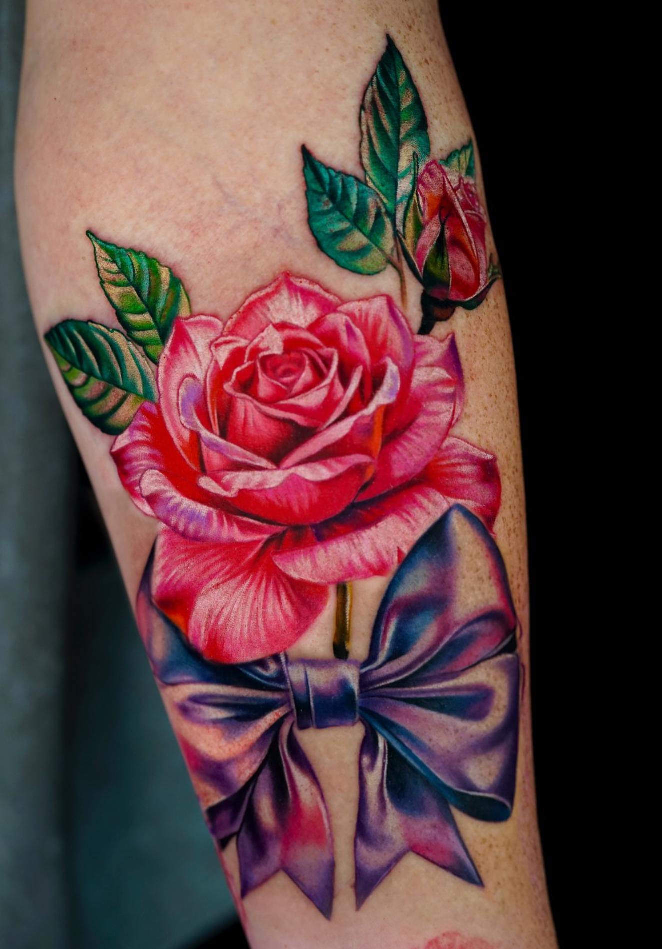 Colorful realistic rose and bow tattoo on forearm