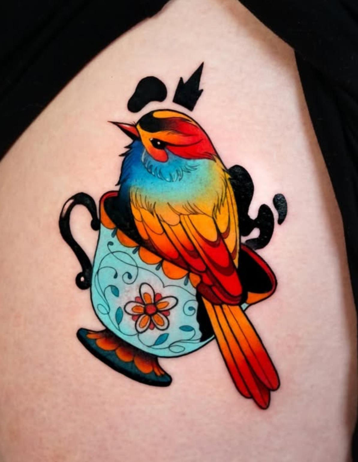 Colorful bird in teacup tattoo on upper arm