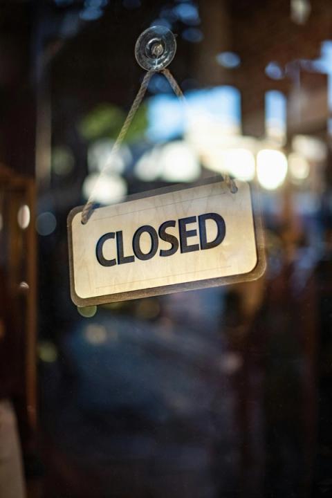 Et skilt med teksten Closed hænger på en glasdør.