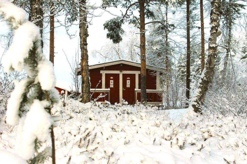 Red single cottage in a snowy forest at Ivalo River Camping