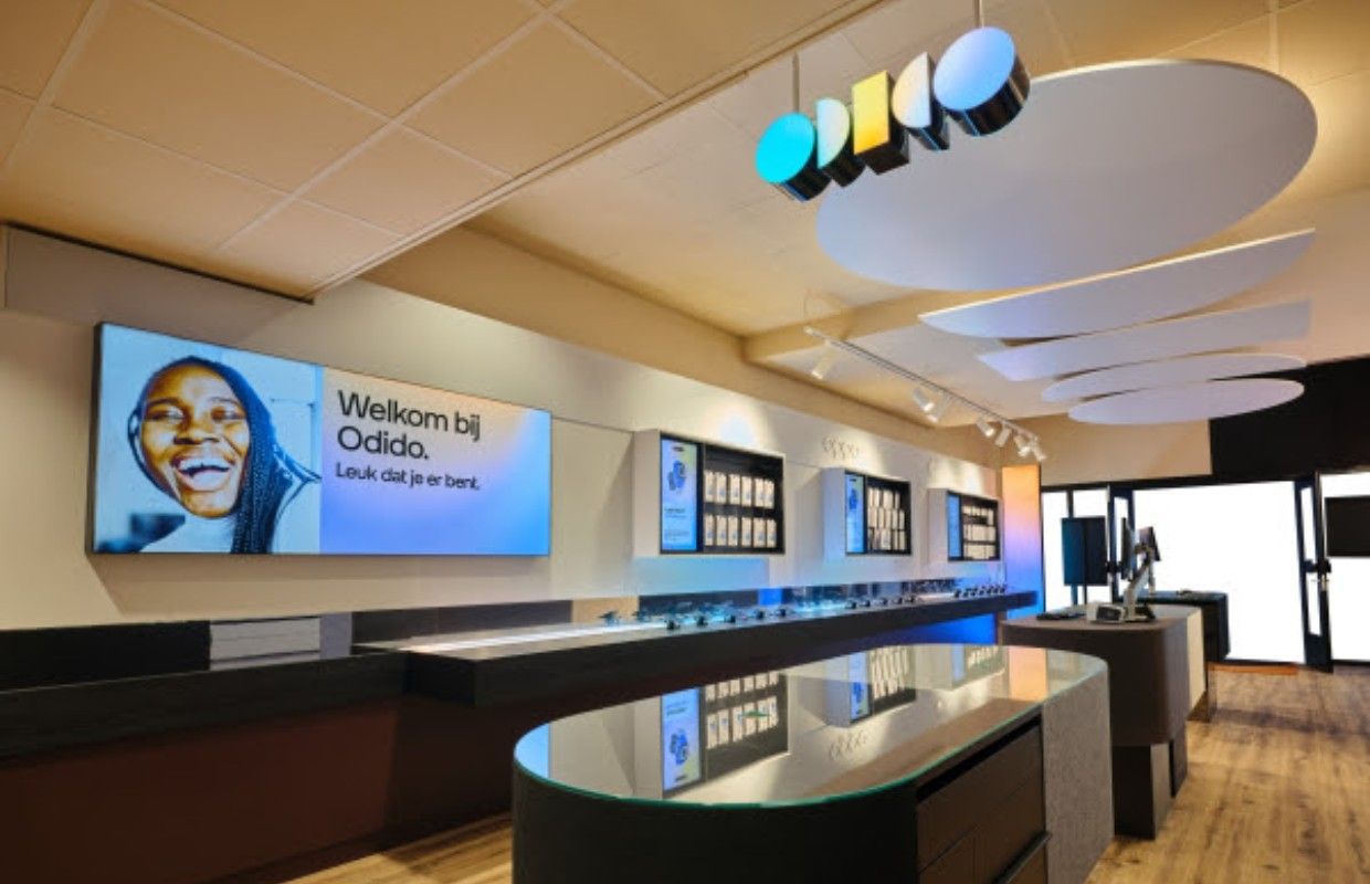 Interieur van een Odido-winkel met het logo aan het plafond en een scherm met 'Welkom bij Odido. Leuk dat je er bent.'